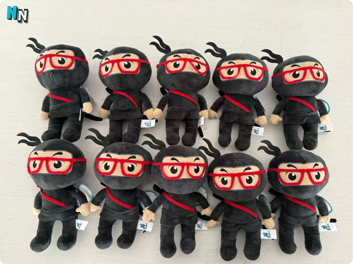 Plush ninja toys with red glasses arranged in a grid on a light background.